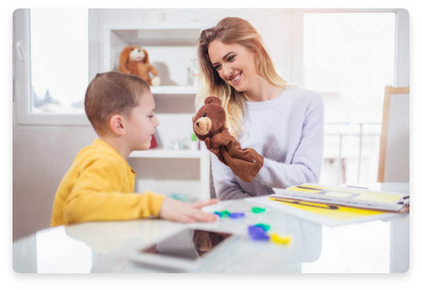 Woman using a teddy bear to help teach a boy